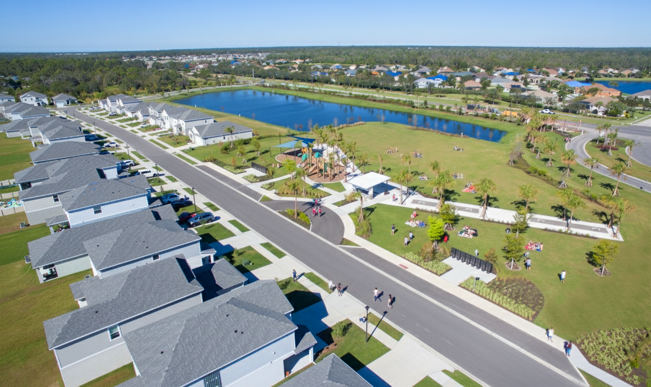 overhead view of new construction housing development with landscaped park, pond, and rows of modern houses