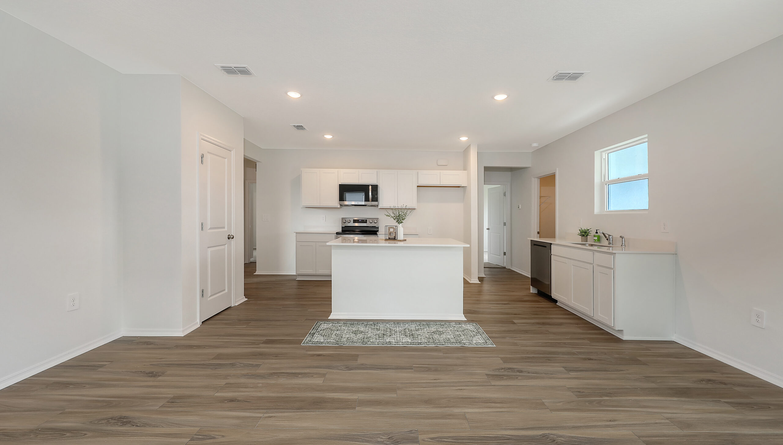 modern white kitchen with center island, stainless steel appliances, recessed lighting, and wood-look flooring